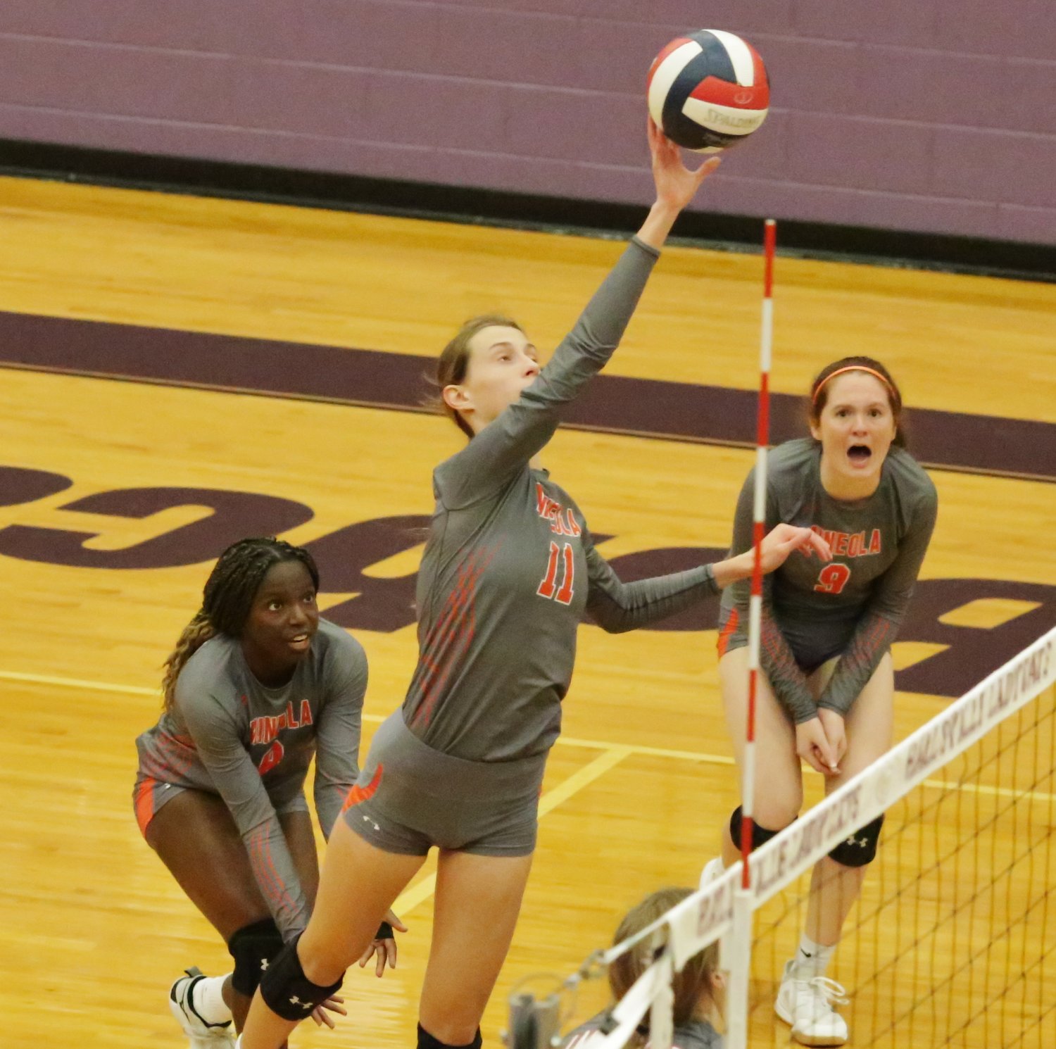 Shylah Kratzmeyer and Gracie Finley flank Olivia Hughes as she makes a play at the net.
